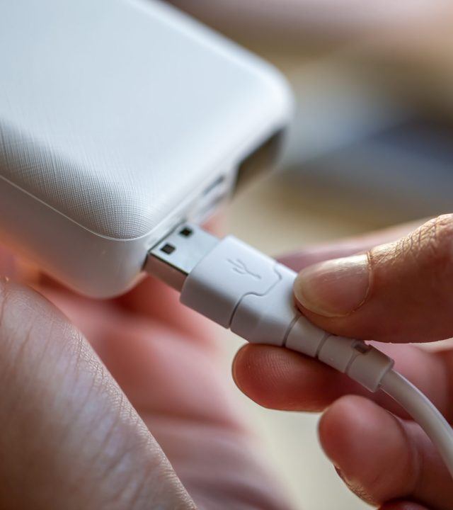 woman's hand holding white usb cable and white power bank.